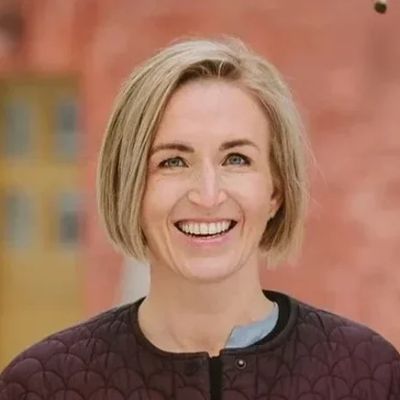 Nainen lyhyillä vaaleilla hiuksilla hymyilee kameralle